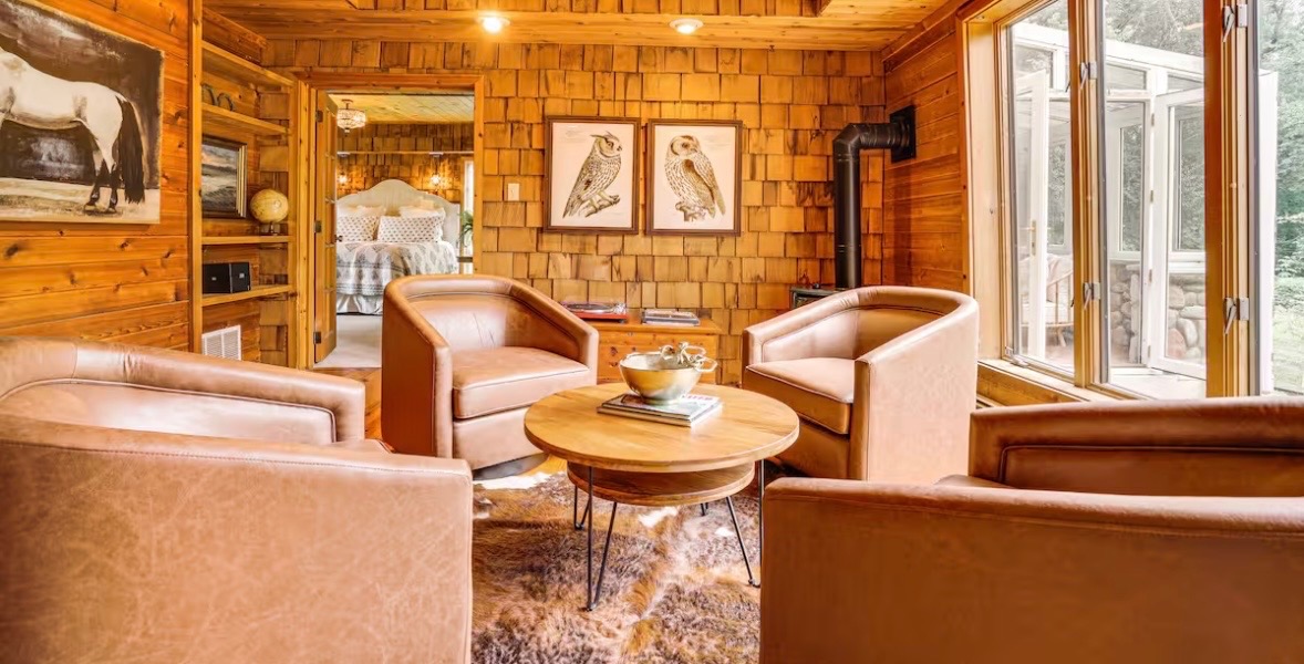 Rustic wood-paneled sitting room with leather chairs
